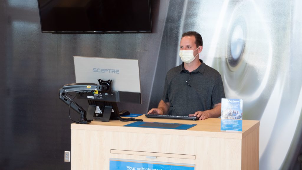 Man standing at front desk of Quick Lane Tire & Auto Center wearing a face mask